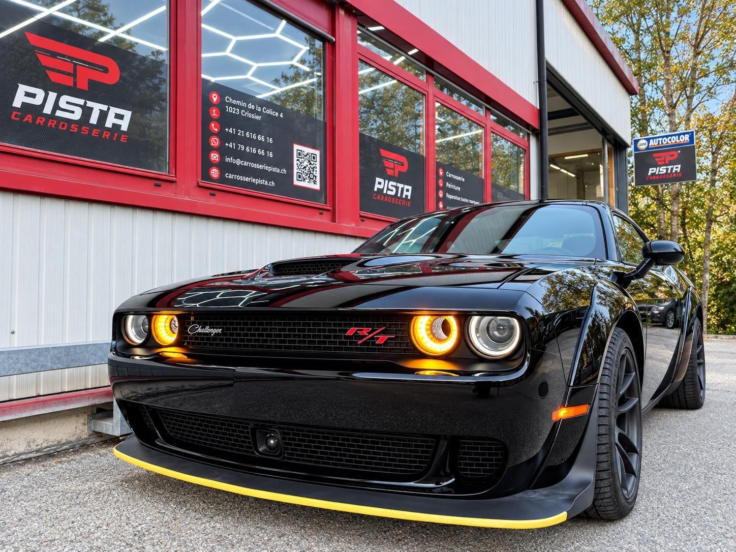 Coupé sportif noir devant l'atelier de Carrosserie Pista