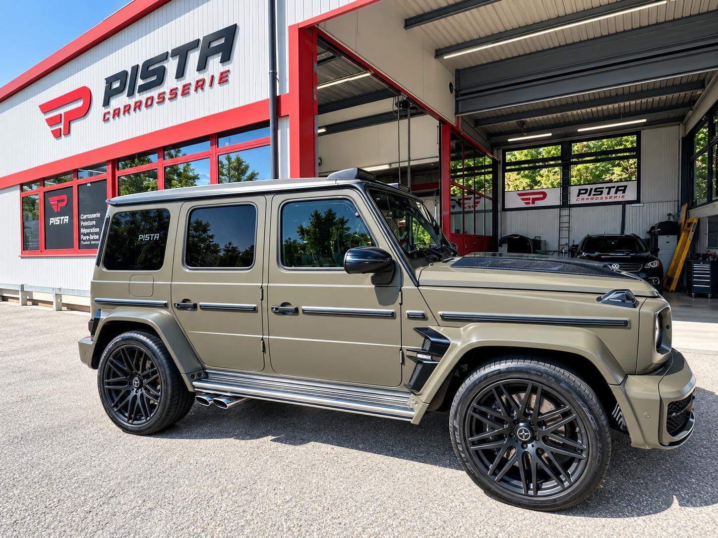 SUV tout-terrain vert olive à la finition mate devant l'atelier de Carrosserie Pista