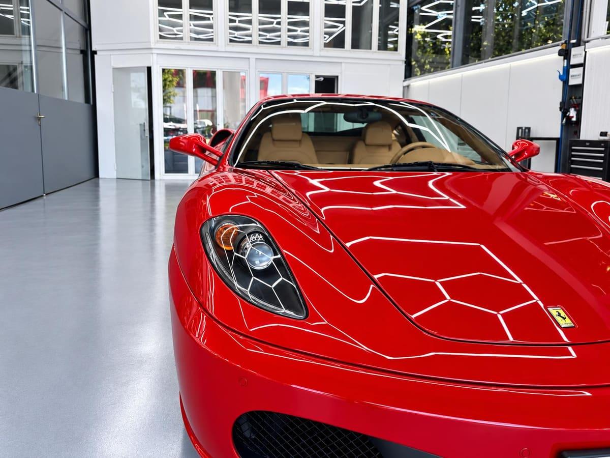 Capot rouge brillant reflétant l'éclairage hexagonal de l'atelier de Carrosserie Pista